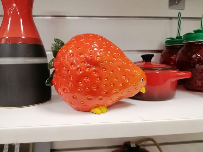 Strange and spectacular second-hand find: a strawberry-shaped ceramic bird on a store shelf.