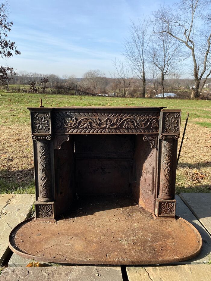 Ornate second-hand fireplace outdoors, showcasing intricate designs against a scenic landscape.