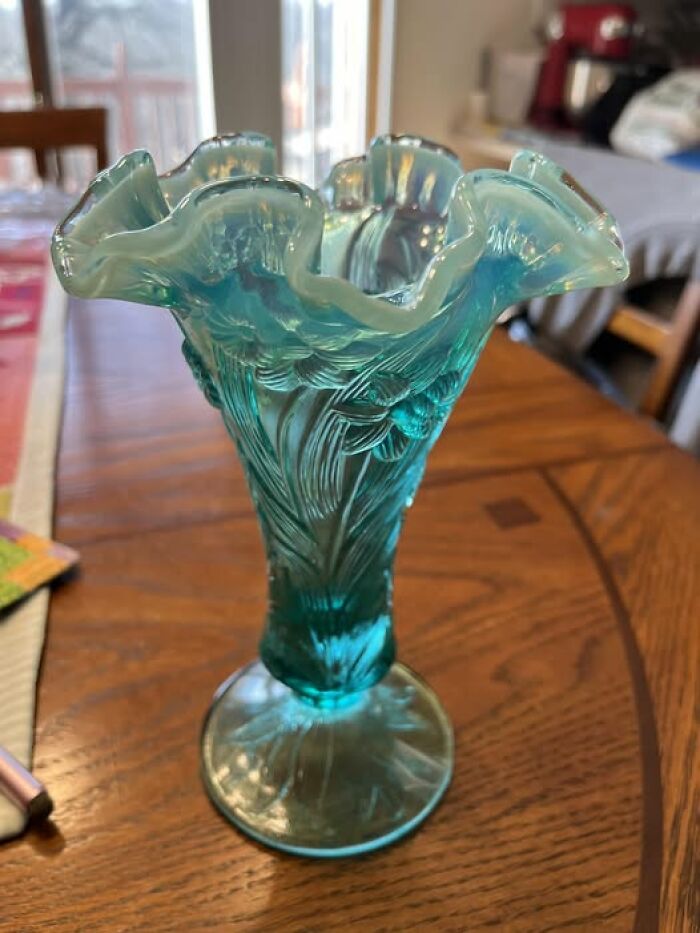 Antique blue glass vase with intricate patterns, a unique second-hand discovery on a wooden table.