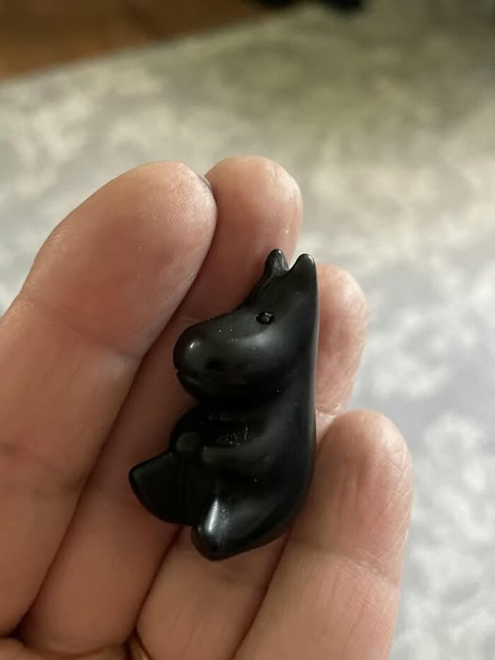 Small black figurine held in hand, representing a strange and spectacular second-hand discovery.