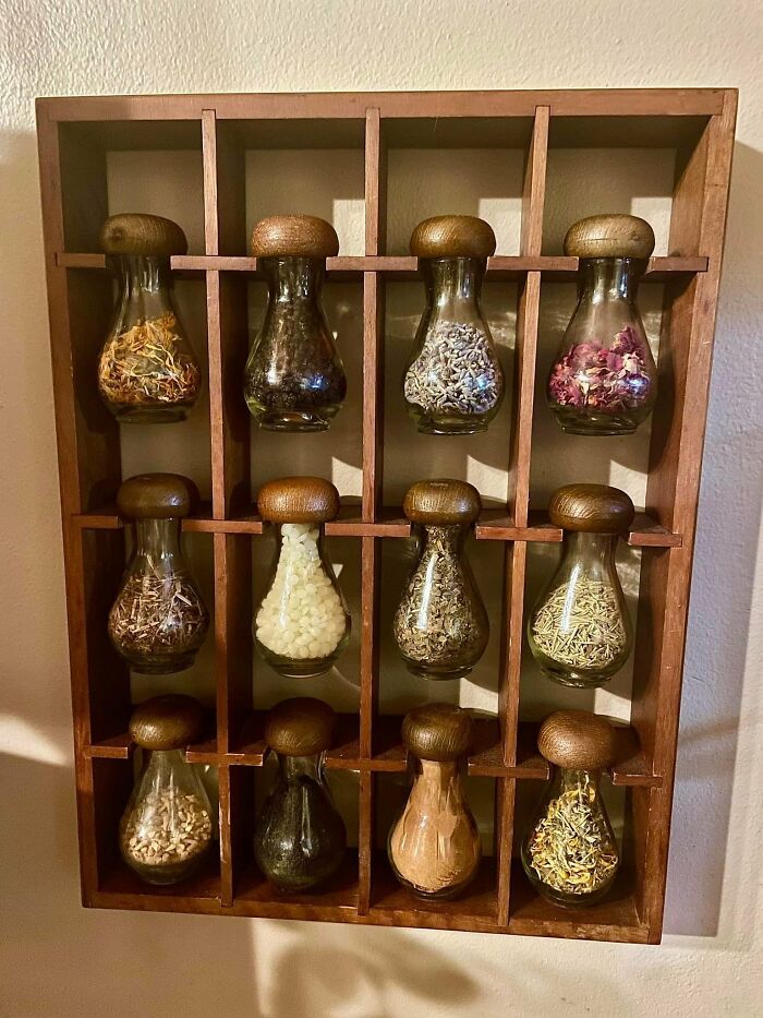 Wall-mounted wooden spice rack with 12 glass jars, showcasing second-hand discoveries.