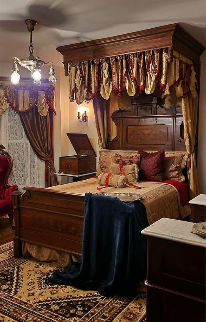 Victorian-style bedroom showcasing a second-hand antique bed with ornate drapes and elegant decor.