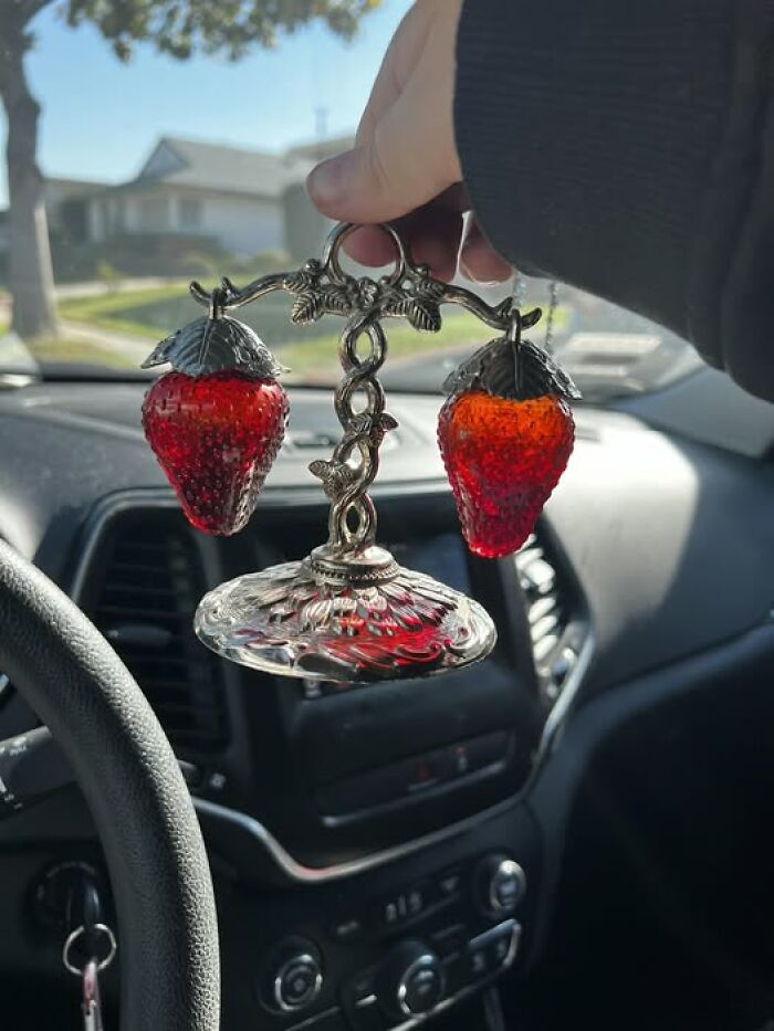 Decorative strawberry-shaped lamp held inside a car, showcasing a strange second-hand find.