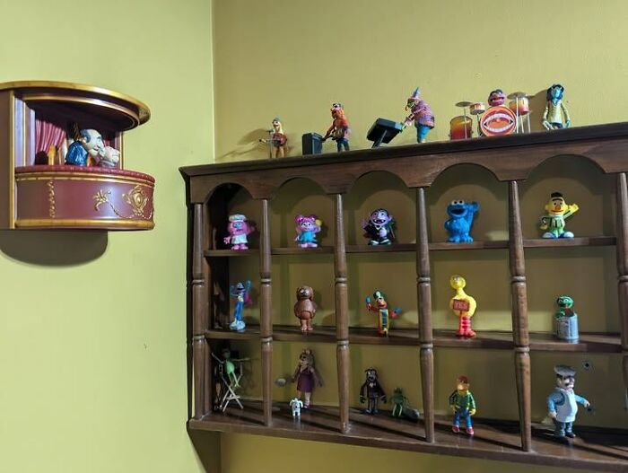 Strange and spectacular second-hand discoveries: a shelf of various colorful figurines against a yellow wall.