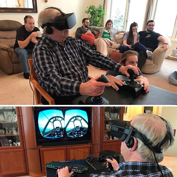 Elderly man enjoying a VR flight simulation with family during a wholesome Christmas gathering.