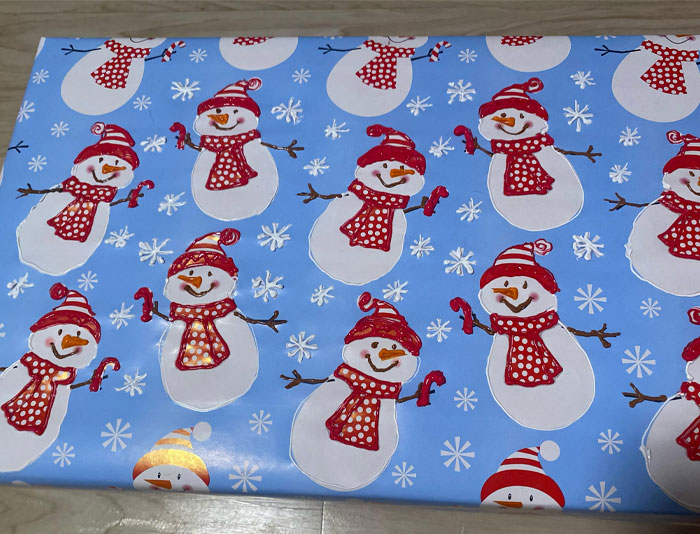 Blue Christmas wrapping paper with cheerful snowmen in red scarves and hats, perfect for wholesome festive moments.