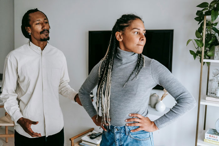 A couple arguing in a living room, showcasing tension and disagreement, linked to a dispute over an apology.