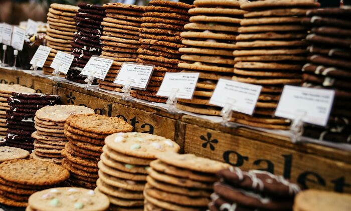 Stacks of assorted cookies at a market stall, labeled with different flavors, highlighting unexpected variety.