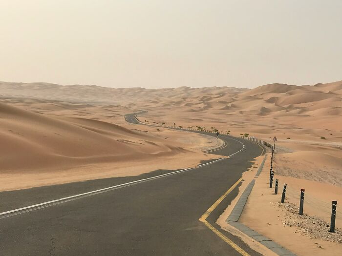 A winding road through expansive desert sand dunes, symbolizing unexpected journeys.