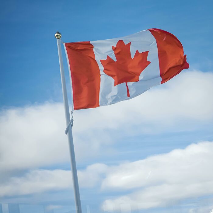 Canadian flag waving against a cloudy sky.