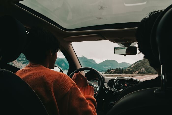 People inside a car driving on a scenic mountain road, emphasizing unexpected travel adventures inspired by a simple text.