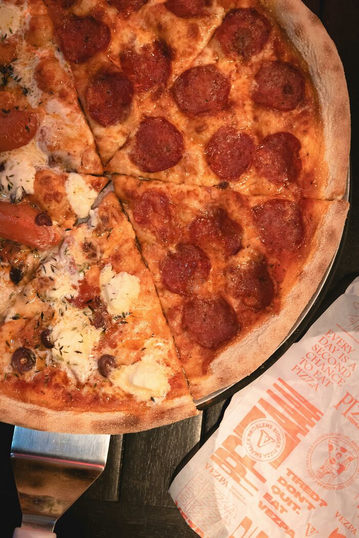 Pepperoni pizza with slices missing, served on a wooden table.