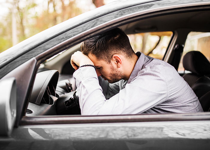 Man in car looking distressed, pondering public proposal situation.