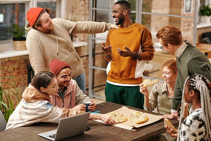 Friends gathered around a table, enjoying pizza and discussing travel plans to Japan.