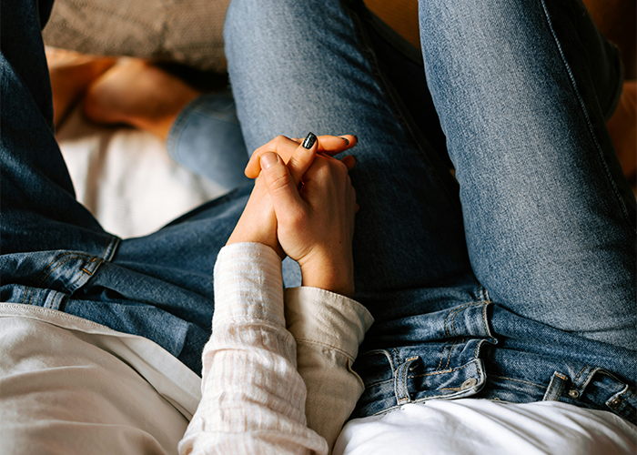 Couple holding hands, wearing casual denim jeans, symbolizing relationship challenges.