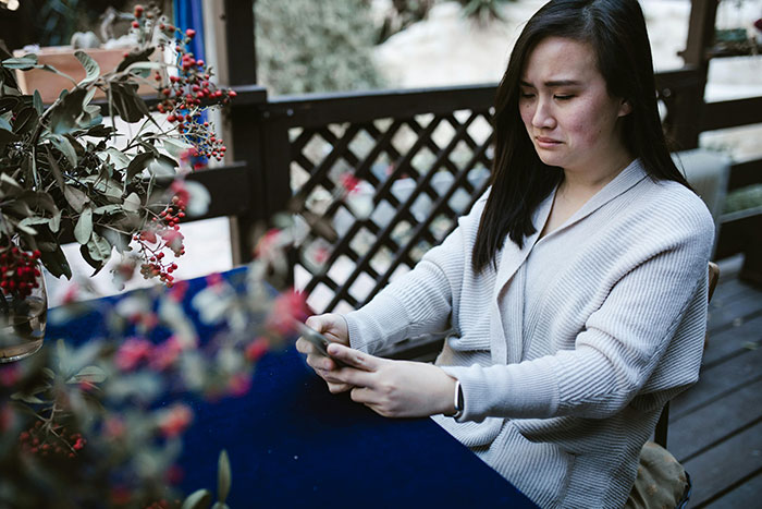 Woman contemplating holiday gifts at an outdoor table, surrounded by festive decorations.