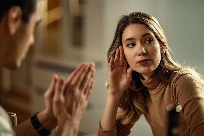 Woman listening intently to someone with hands gesturing.