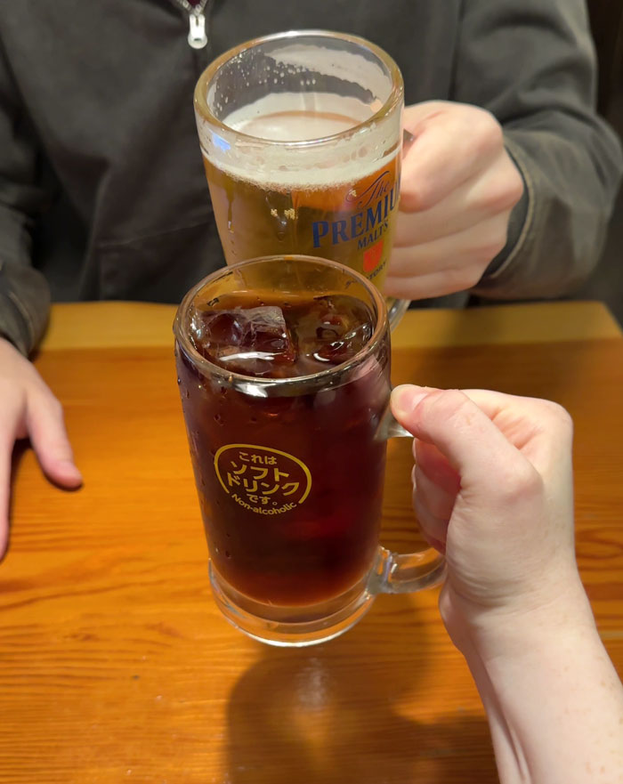 People clinking glasses in Japan, highlighting work rules with drinks on a wooden table.