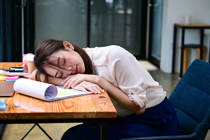 Woman exhausted at work, highlighting Japan's oppressive work rules.