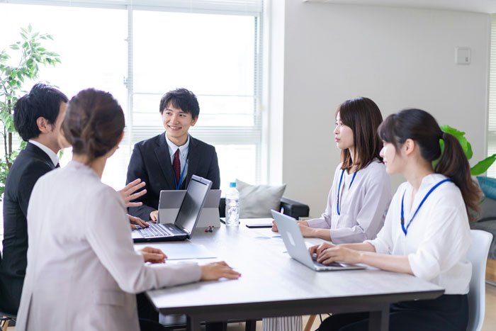 Japanese office workers in a meeting, with laptops and documents on the table.