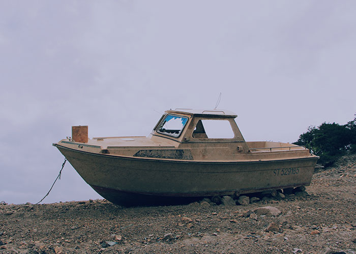 A deserted boat sits on rocky shore, creating a wild sighting at sea with its unexpected location.