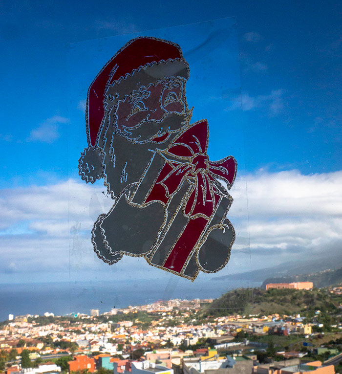 Santa decal with gift on a window overlooking a scenic town, highlighting Christmas presents theme.