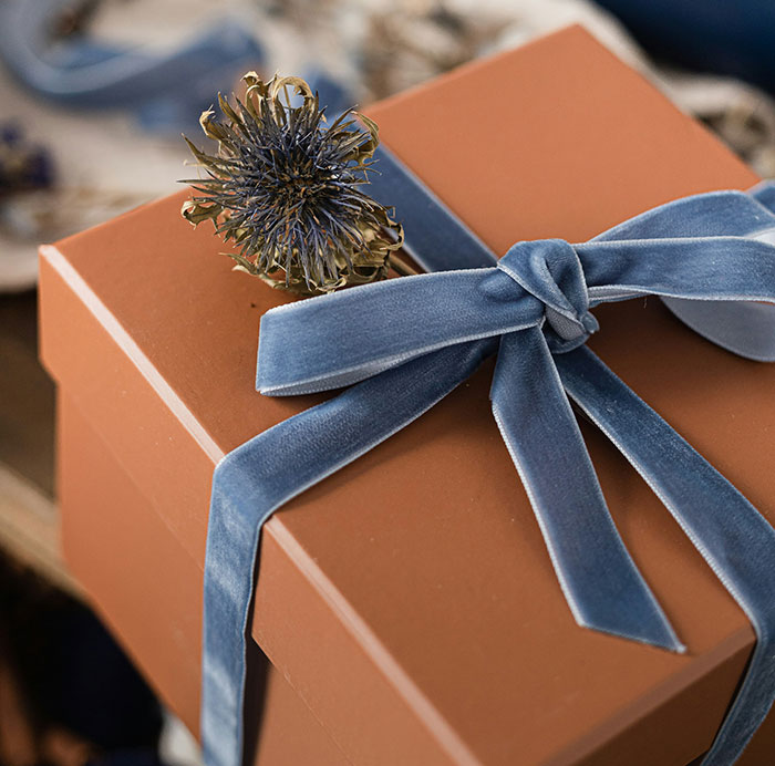 Brown gift box with a blue velvet ribbon, symbolizing Christmas presents ruining holiday spirit.