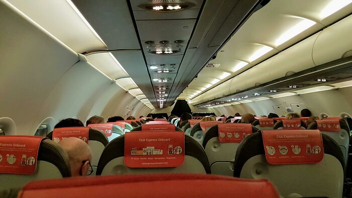 Interior of a crowded airplane during a long flight experience.