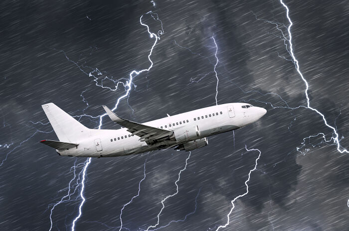 Airplane flying through storm with lightning, symbolizing worst experience on a long flight.