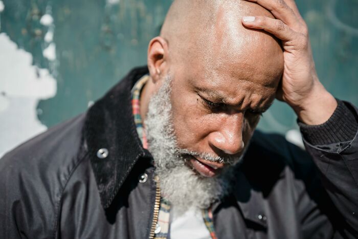 Man holding his head, expressing stress and fatigue from a difficult long flight experience.