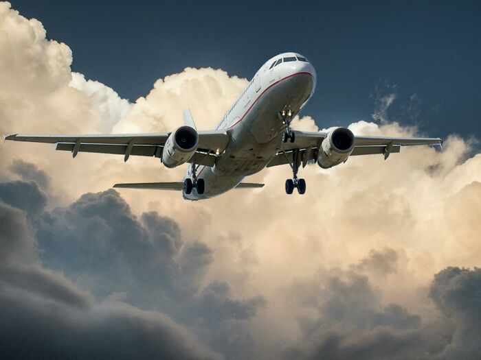 Airplane flying through cloudy sky, depicting worst experience during long flight.