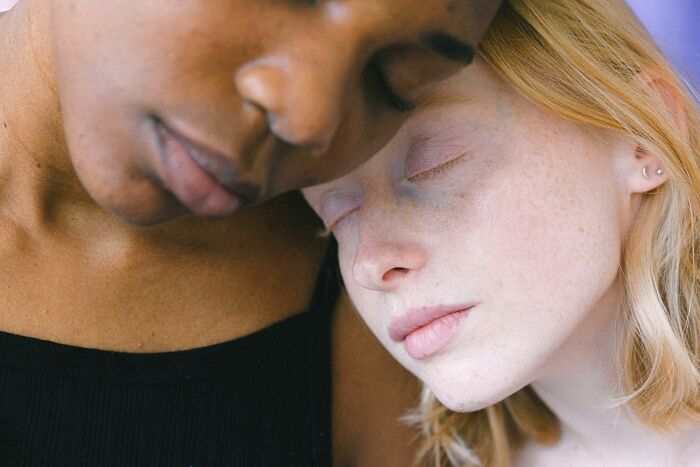 Two women leaning on each other, eyes closed, reflecting the fatigue of the worst experience on a long flight.