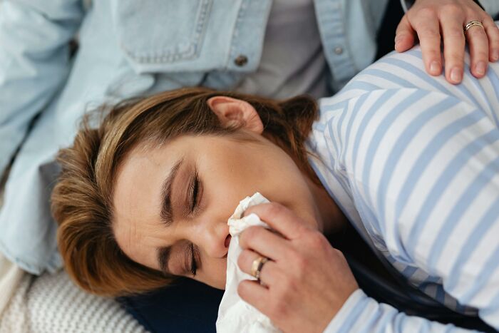 Person experiencing discomfort, lying down and holding a tissue, illustrating a worst experience on a long flight.