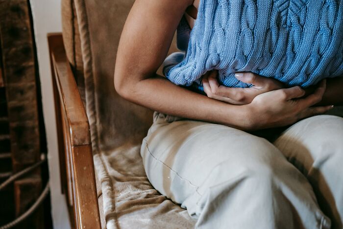 Person clutching stomach in discomfort, representing worst experience on a long flight.