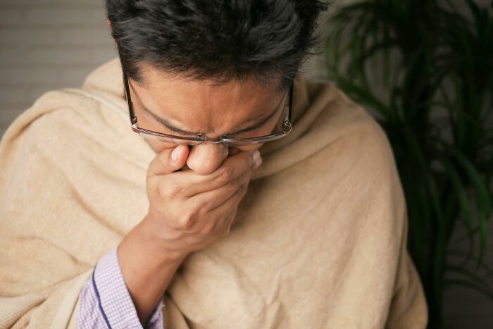 Person covering mouth with hand, experiencing discomfort on a long flight.