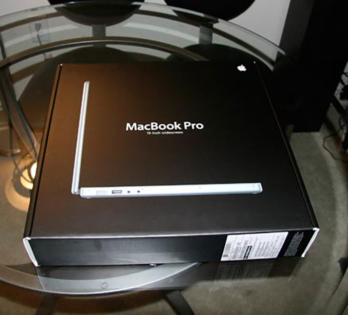 MacBook Pro box on a glass table, possibly a Secret Santa gift.