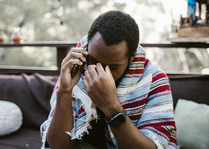 Stressed person on a phone call, wrapped in a striped blanket, symbolizing worst things happened at Christmas.