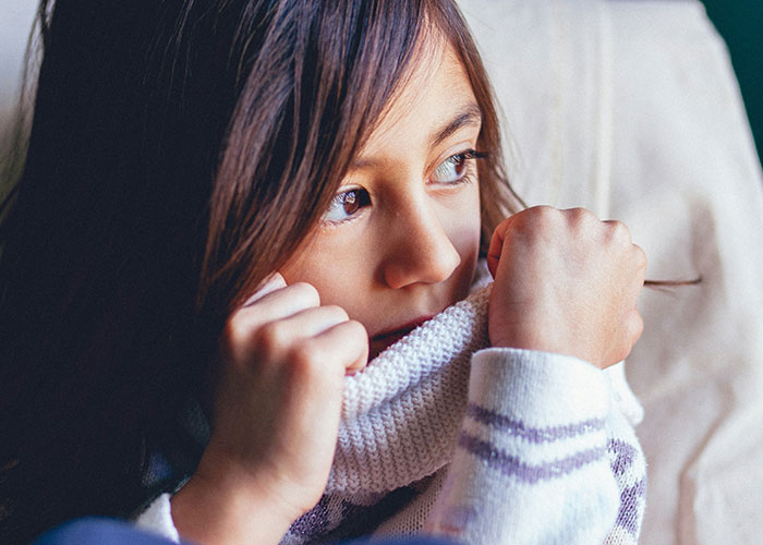 Child wrapped in a sweater, looking thoughtful, representing the worst things happened during Christmas experiences.