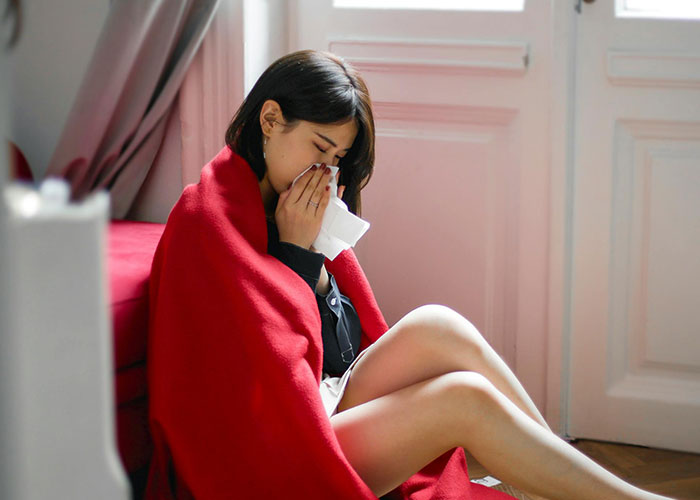 Woman wrapped in a red blanket, sitting on the floor, appearing upset during Christmas.