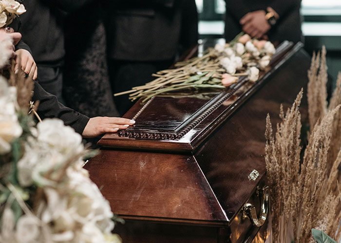 A somber Christmas scene with mourners placing flowers on a wooden coffin.