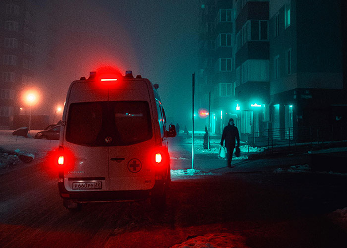 Ambulance with flashing lights on dark, snowy street during Christmas night.