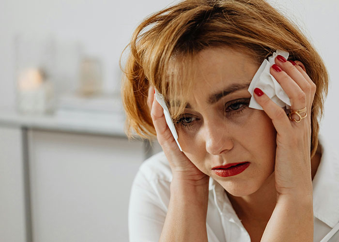 A woman looking distressed with tissues in hand, representing holiday stress or worst things about Christmas.