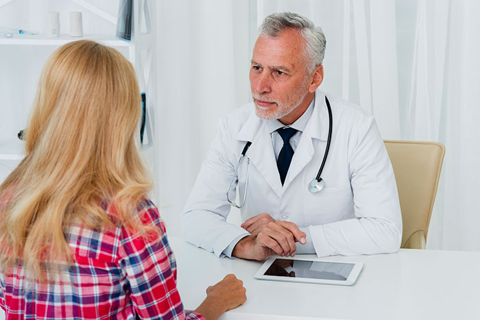 A woman discussing medical binder hack with a doctor at a clinic.