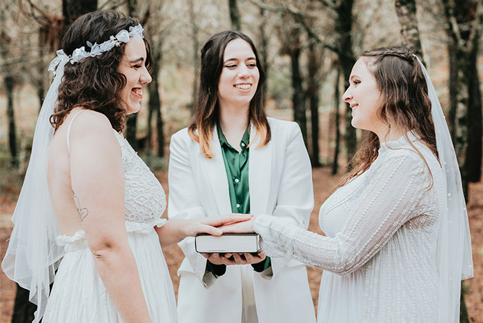 Women in wedding attire holding hands outdoors, symbolizing friendship and relationships.