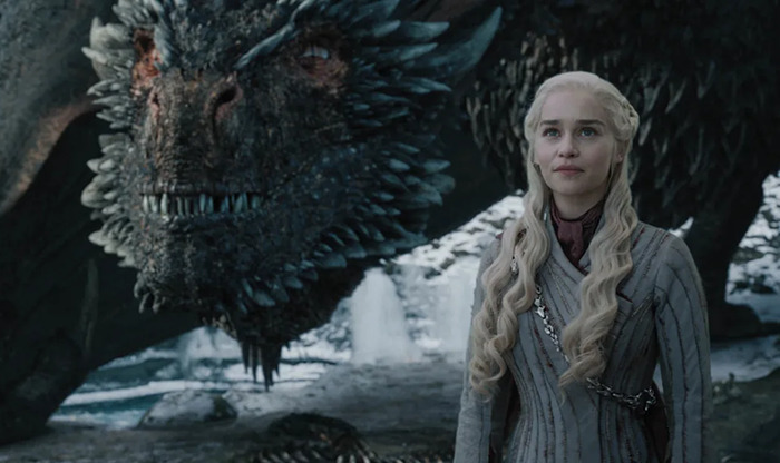 Khaleesi standing beside a dragon in Game of Thrones scene.