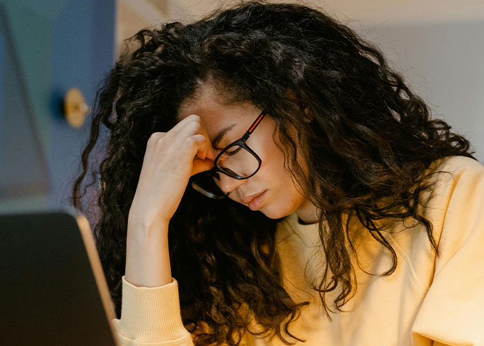 Woman in glasses sitting at a desk, looking upset over trust fund issues.