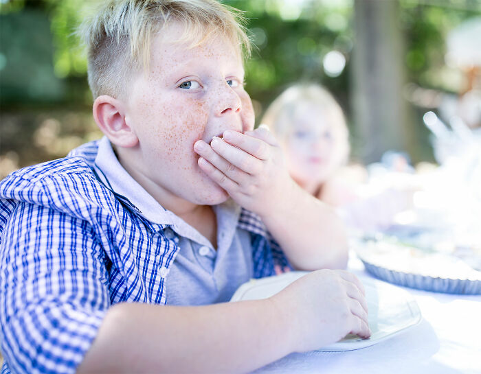 Child at a picnic, eating and looking thoughtful, representing realizations as they age about what was once overlooked.