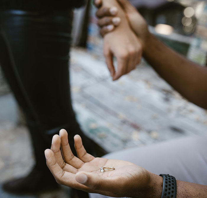 Man holding ring, woman's hand held; represents marriage influencer scam.