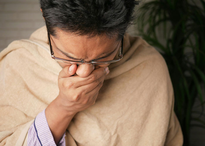 Person with glasses covering mouth, possibly cringing, representing awkward job interview moments.