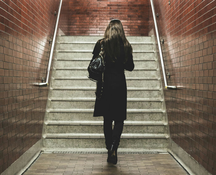 Woman in a black coat walking up stairs, representing a quality hack in urban navigation.